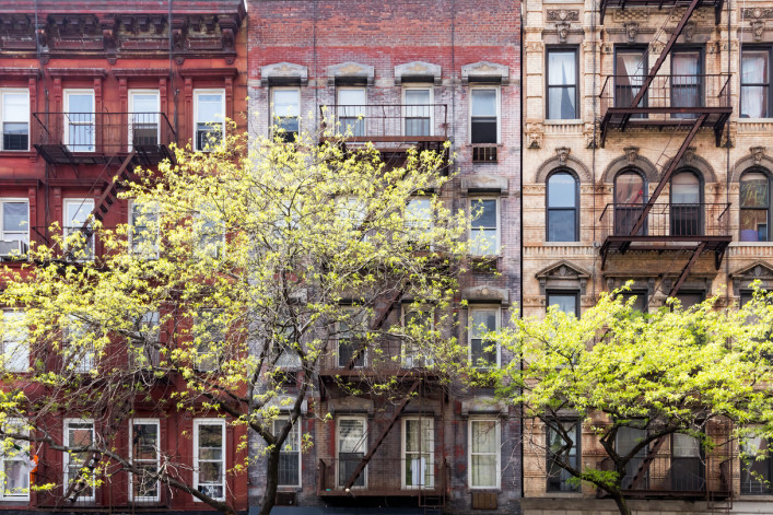 a row of new york city apartments with trees in front. a row of new york city apartments with trees in front.